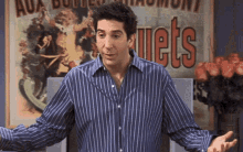 a man in a blue striped shirt is standing in front of a poster that says " jets "