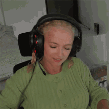 a woman in a green sweater is wearing headphones
