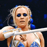 a woman in a blue and white wrestling outfit is holding a white pole