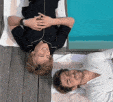 two men laying next to each other on a wooden deck