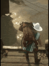 a man wearing a cowboy hat is carrying a large animal on his back