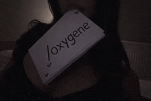 a woman holds a piece of paper with the word oxygene written on it