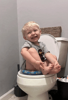 a little boy is sitting on a toilet with his feet on the seat