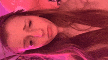a woman with long hair is laying on a bed with a pink background