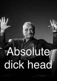 a man sitting in a chair with his hands in the air and the words absolute dick head behind him