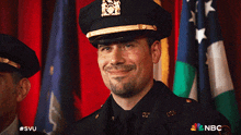 a man in a police uniform is smiling in front of a nbc ad