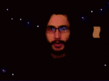 a blurry picture of a man with a beard and glasses in a dark room