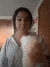 a girl in a grey hoodie is holding a white object in her hand