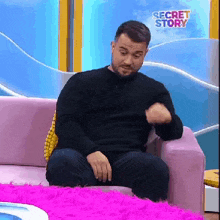 a man is sitting on a couch in front of a screen that says secret story on it