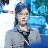 a woman wearing glasses and a tie stands in front of a microphone on a stage