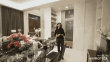 a woman stands in front of a dining table with flowers on it and the words made in animatica on the bottom