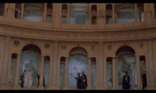 a group of men dressed in costumes are standing in a room . one of the men has a crown on his head .