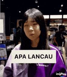 a woman in a purple jacket holds a sign that says apa lancau