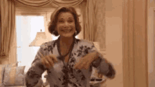 a woman is dancing in a living room with her arms outstretched and smiling .