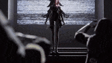 a woman is standing on a stage in front of a large screen while a man looks on .