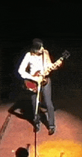 a man playing a guitar on a stage with a microphone
