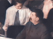 a man with a mustache is talking to a woman in a white shirt