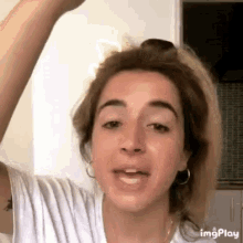 a woman is holding her hair in a ponytail and talking .