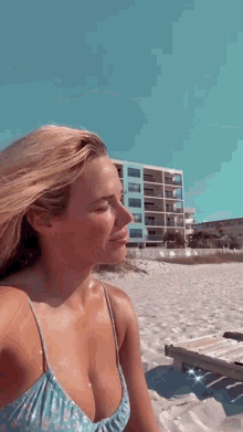 a woman in a bikini is sitting on the beach