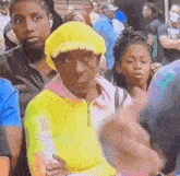 a man wearing a yellow hat is sitting in a crowd .