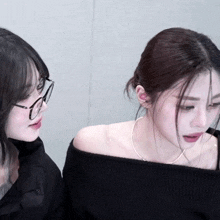a woman wearing glasses and a black off the shoulder top