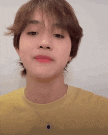 a close up of a person wearing a yellow shirt and a necklace