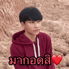 a young man wearing a red hoodie has a heart in front of him that says ' มา ' on it