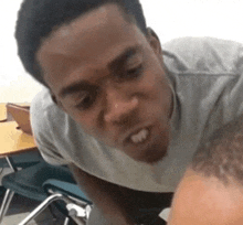 a man in a grey shirt is looking at another man in a classroom