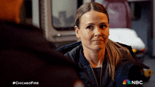 a woman is sitting in front of an ambulance with the nbc logo on the bottom right