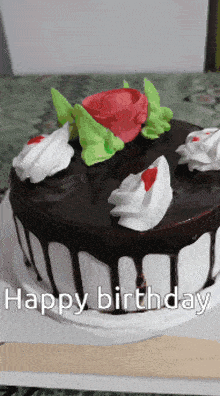 a chocolate birthday cake with white frosting and a red rose on top