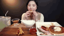 a woman sitting at a table eating a sandwich