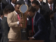 a man in a suit and tie is holding a trophy