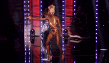 a woman in a gold bodysuit is dancing on a stage in front of a crowd .