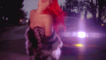 a woman with red hair standing in front of a car