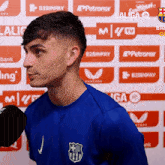 a man in a blue shirt is talking into a microphone in front of a laliga logo