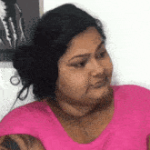 a woman in a pink shirt is making a funny face .