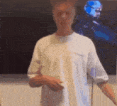 a man in a white shirt is standing in front of a painting of a robot