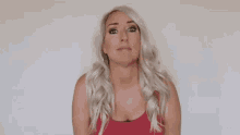 a woman with blonde hair and a red tank top is smiling .
