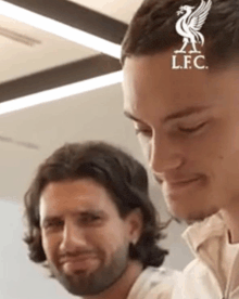 two men are standing next to each other with the lfc logo on their head