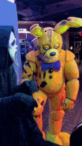 a grim reaper is standing next to a yellow teddy bear costume