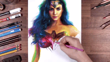 a drawing of wonder woman is being drawn with a pink pencil