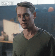 a man in a green shirt is standing in front of a sign that says skyned