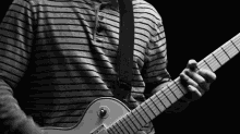 a man wearing a striped shirt is playing an electric guitar