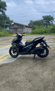 a black scooter is parked on a dirt road in front of a house