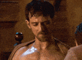 a shirtless man with a towel around his neck is looking down