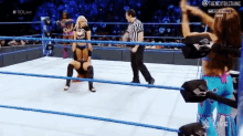 a woman in a wrestling ring with a referee and #sdlive on the screen