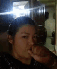 a woman is taking a selfie in a dark room while holding her hand to her mouth .