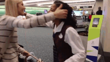 a woman kissing another woman 's head in an airport