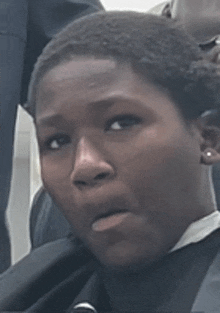 a young man in a graduation cap and gown is making a funny face while sitting in a chair .