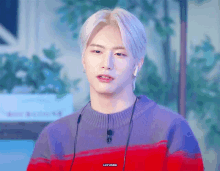 a young man wearing a purple and red striped sweater with headphones around his neck has the word donation on his chest